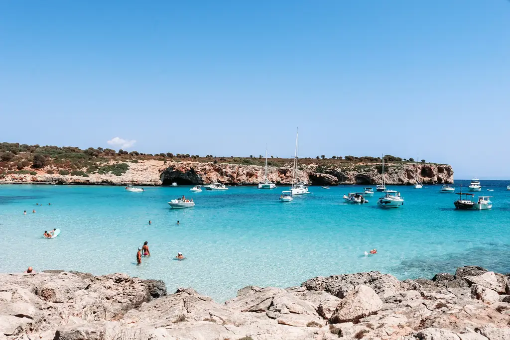 Bucht mit flachem türkisfarbenem Wasser, Booten und Badegästen