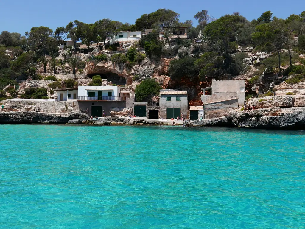 Türkisfarbene Bucht mit Bootshäusern am Felsufer