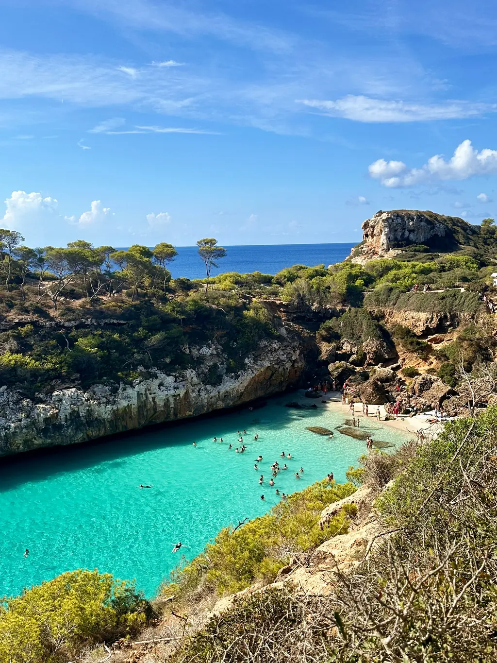 Blick von oben in eine Bucht mit türkisfarbenem Wasser zwischen Felsen