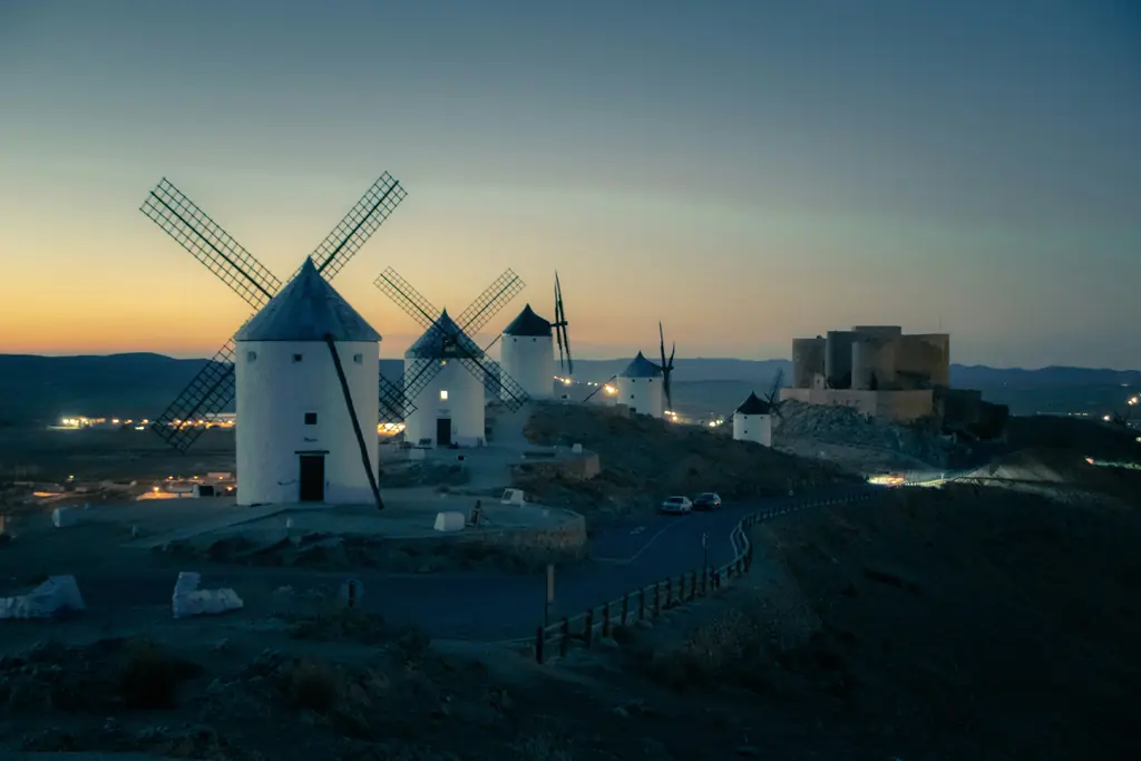 Weiße Windmühlen und eine Burg auf einem Hügel in La Mancha in der Dämmerung