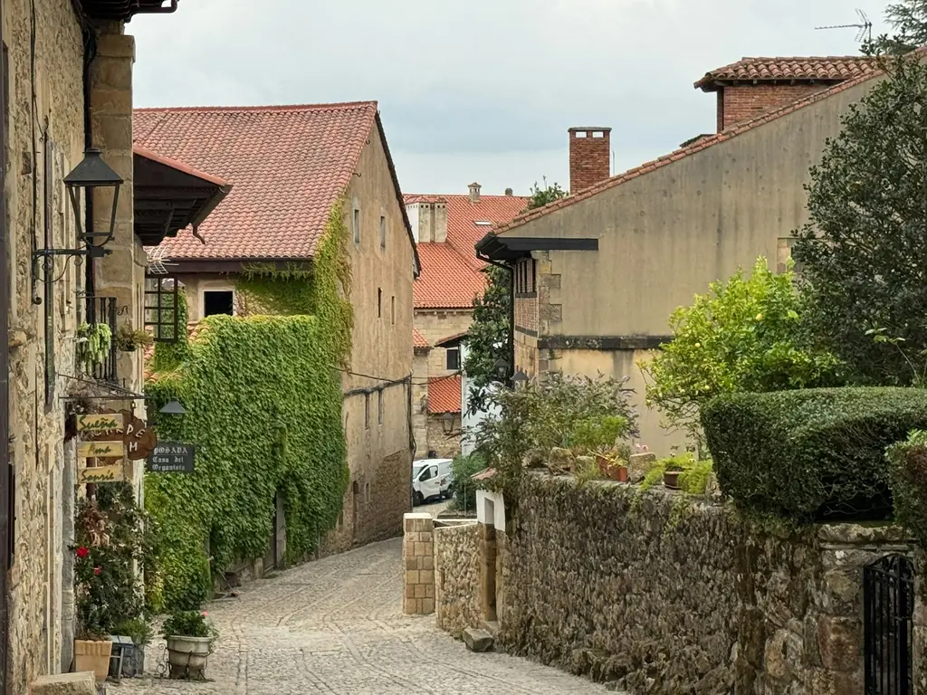 Kopfsteingasse zwischen Steinhäusern mit Efeu in Santillana del Mar